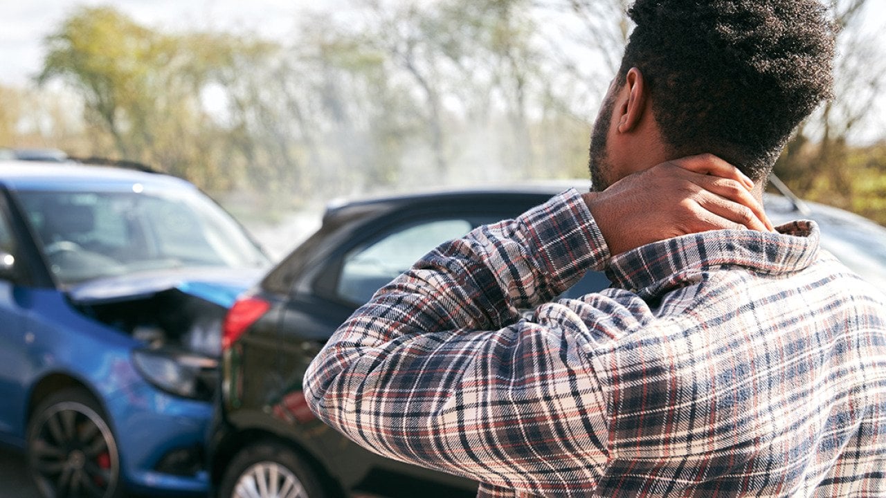 A stressed young man looking at the damage his car caught after an accident.