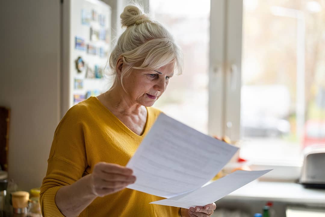 A senior woman reviewing her bill statements.