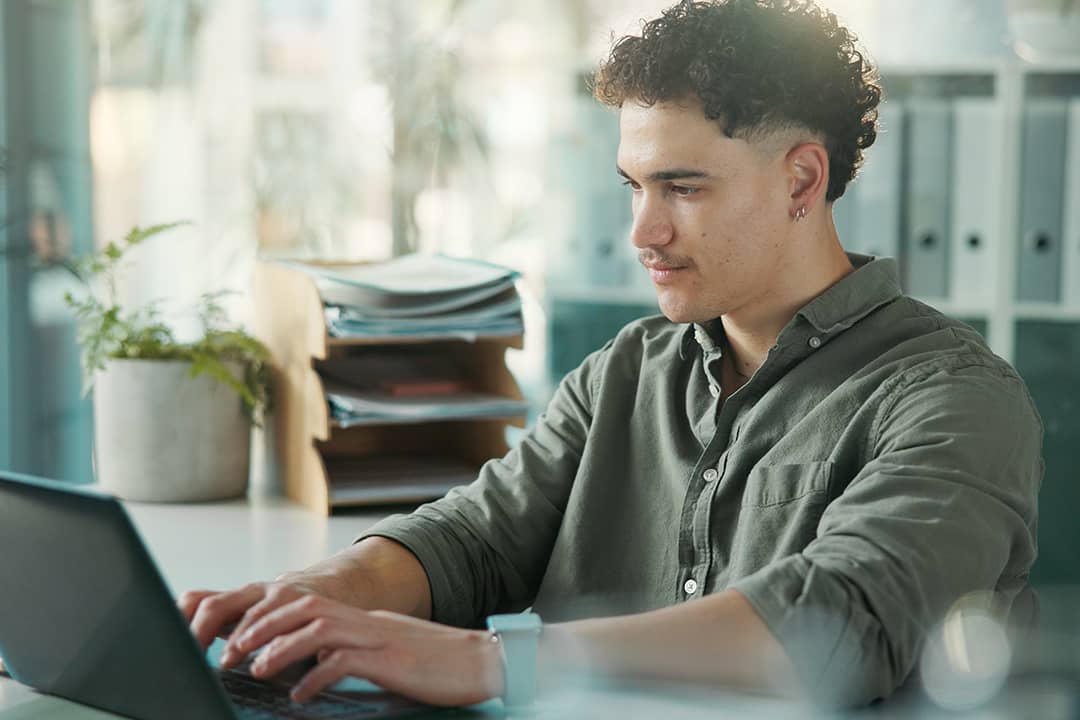 A male employee at work using a laptop.