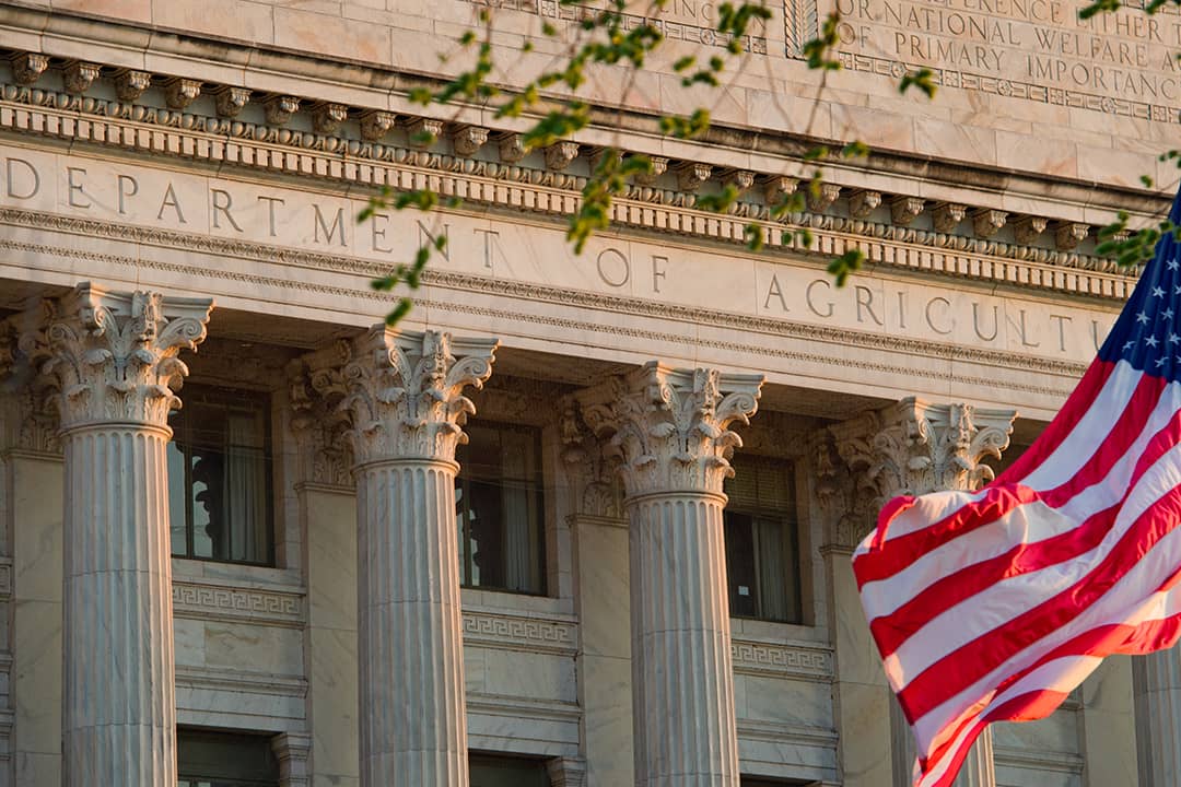 The facade view of the United States' Department of Agriculture office building with the American flag in the front.