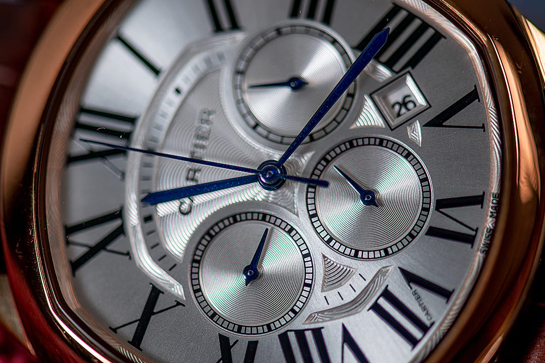 A close-up of a Cartier Drive de Cartier men's watch dial in golden steel color.