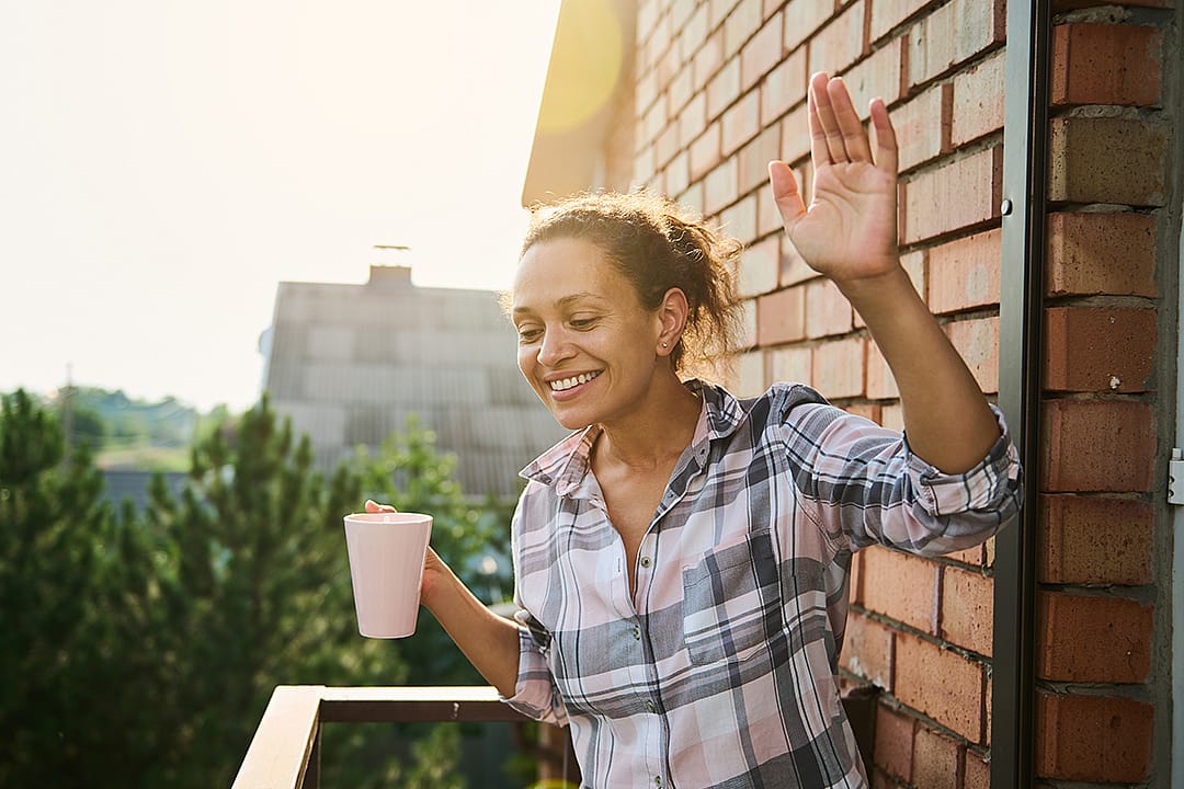 A woman greeting people from her balcony in the morning.