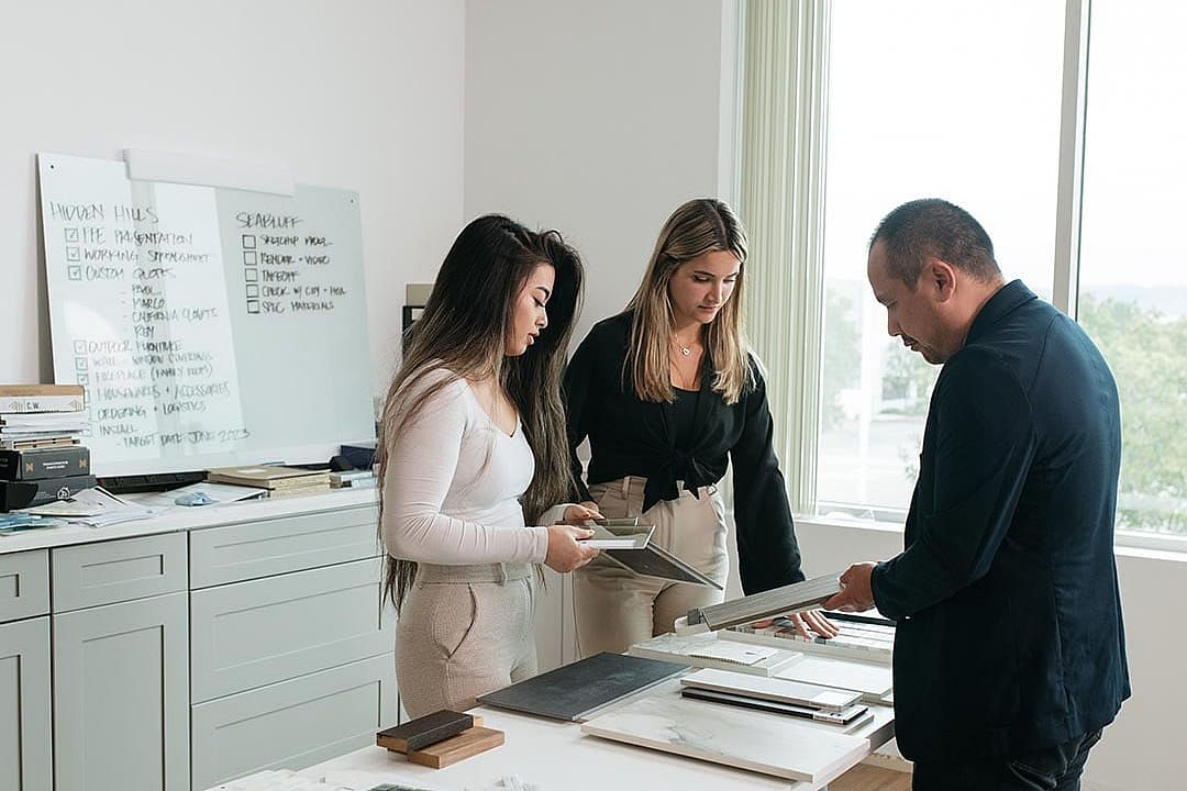 A client and interior designers reviewing physical samples and material selections in a studio.
