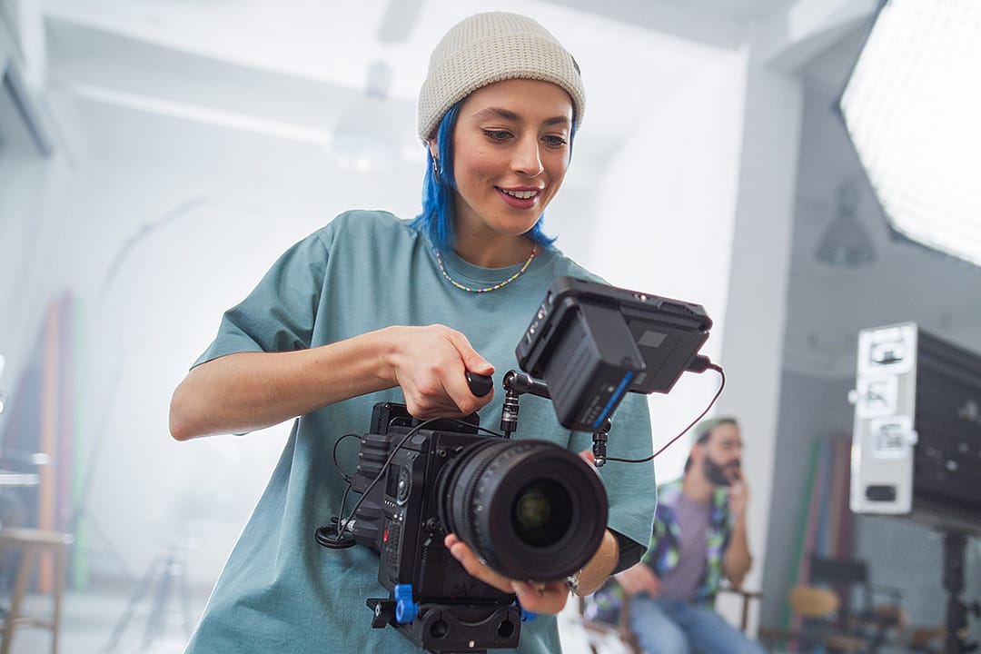 A young female cinematographer working a camera in a studio.