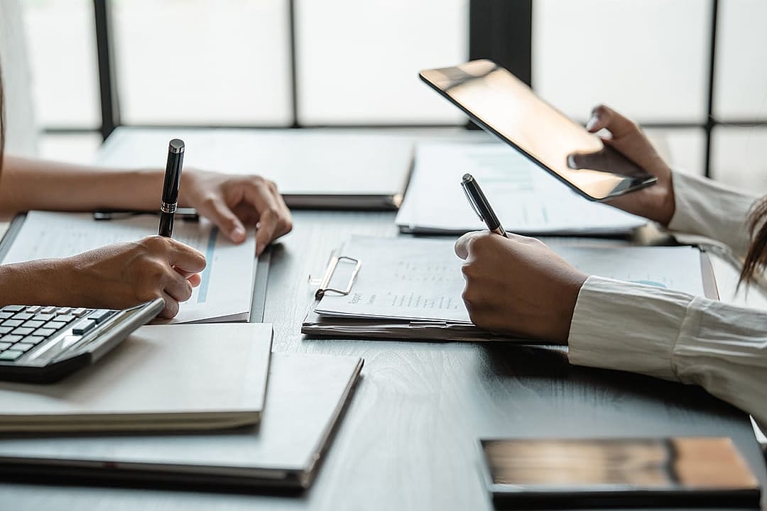 Accountants checking physical reports to finalize project figures.