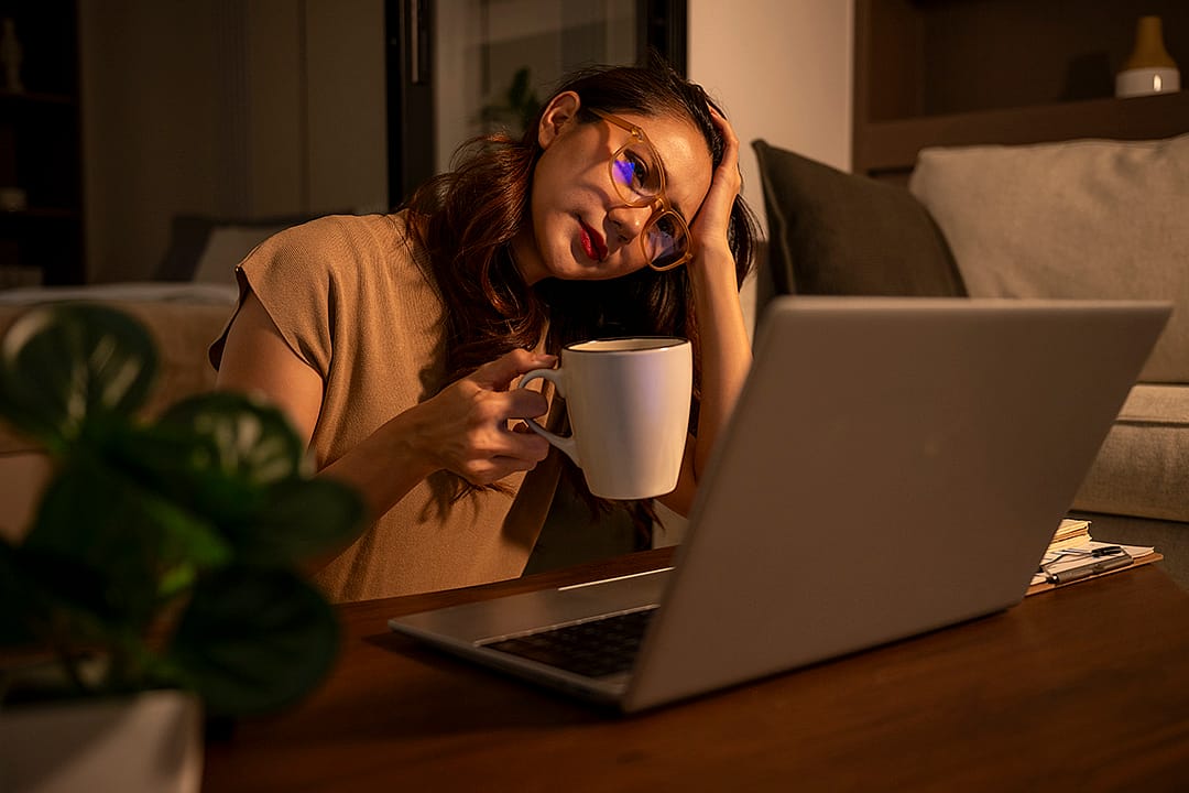 A woman feeling stressed from overworking at night.