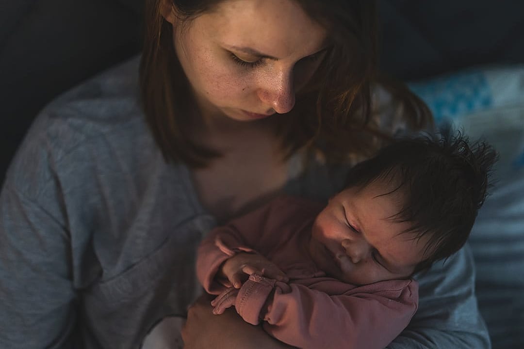A young mother putting her newborn to sleep at night.