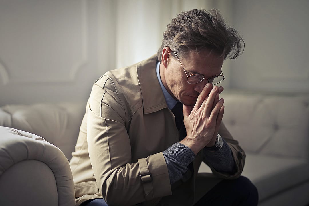 A man sitting on a sofa in deep contemplation