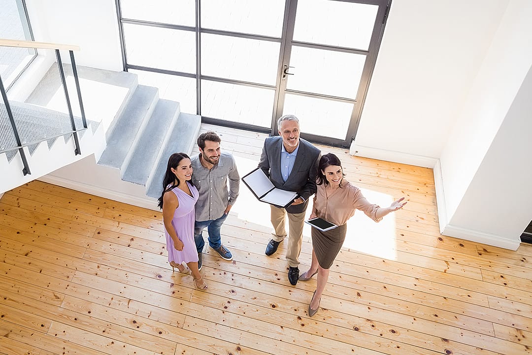 Real estate agents show a young couple the interior of a new house.