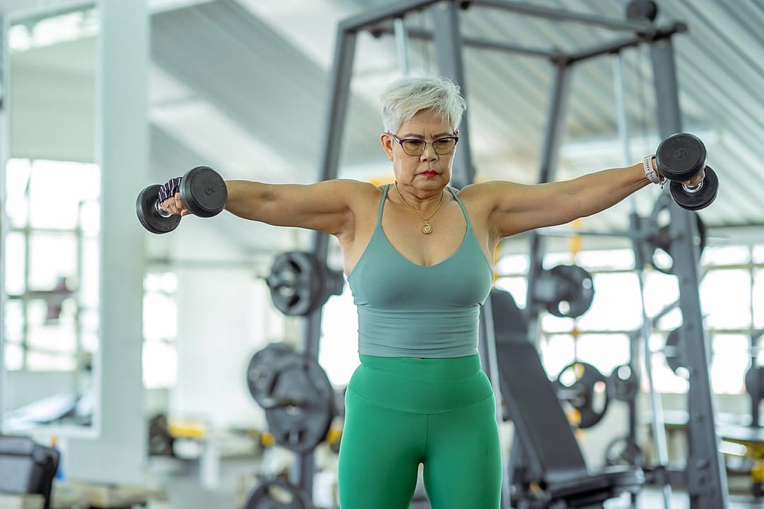 A senior woman working out with weights at the gym.
