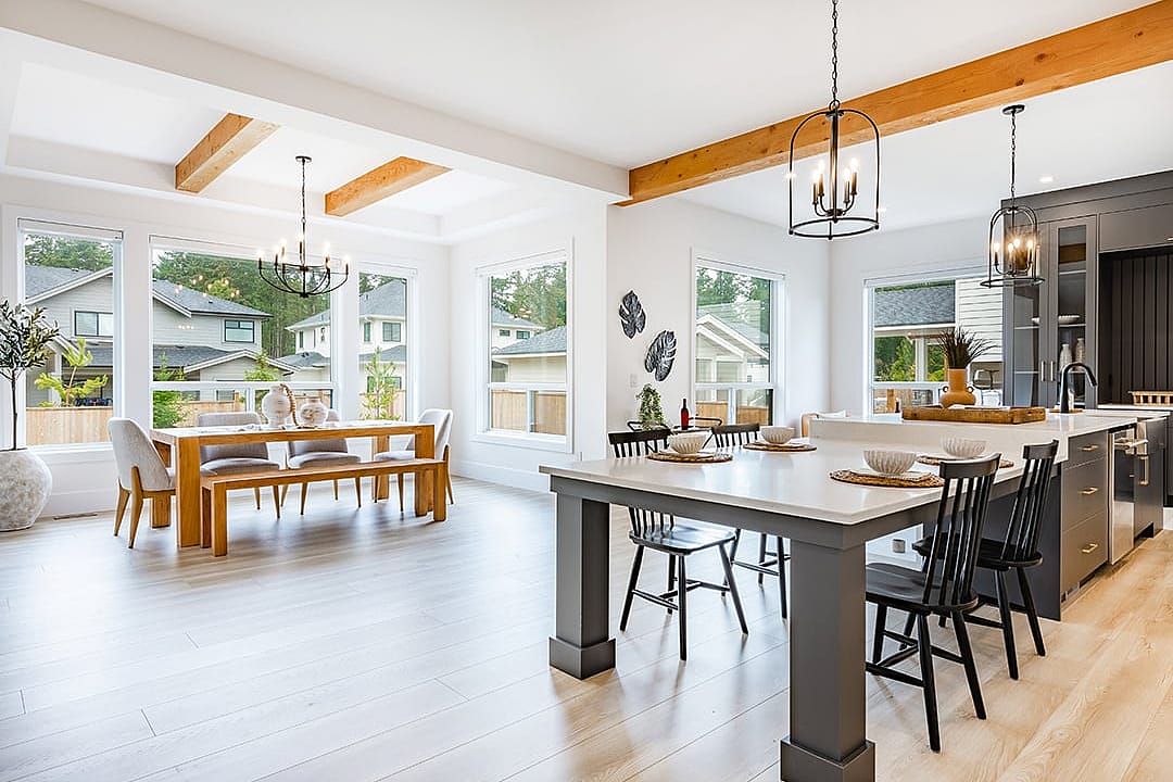 An interior of a modern home's living area, dining, and kitchen with its large glass windows.