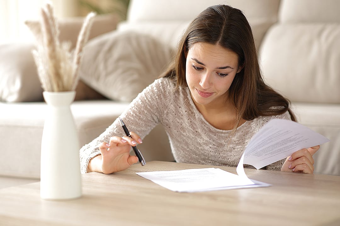 A person reviewing the coverage and cash value of her life insurance policy at home.
