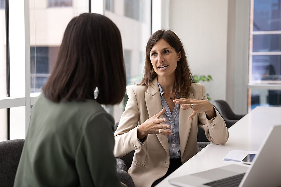 Two businesswomen engaged in a discussion at a meeting.