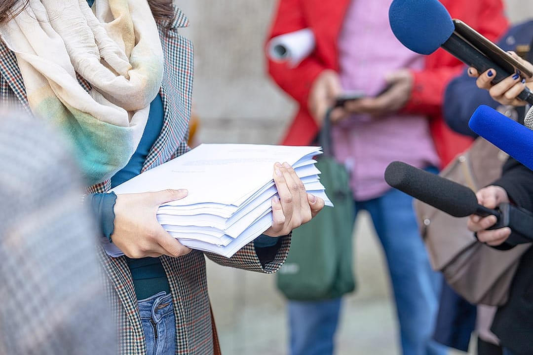 A whistleblower holding relevant documents and speaking to press for a media interview.
