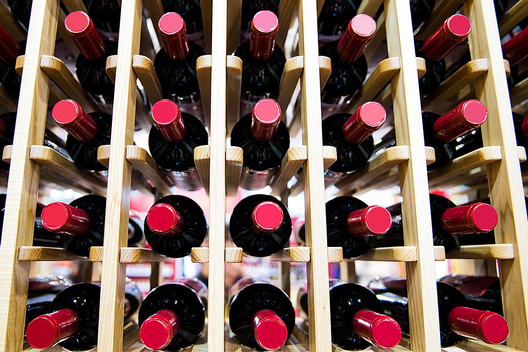 A group of red wine bottles stacked on wooden racks.
