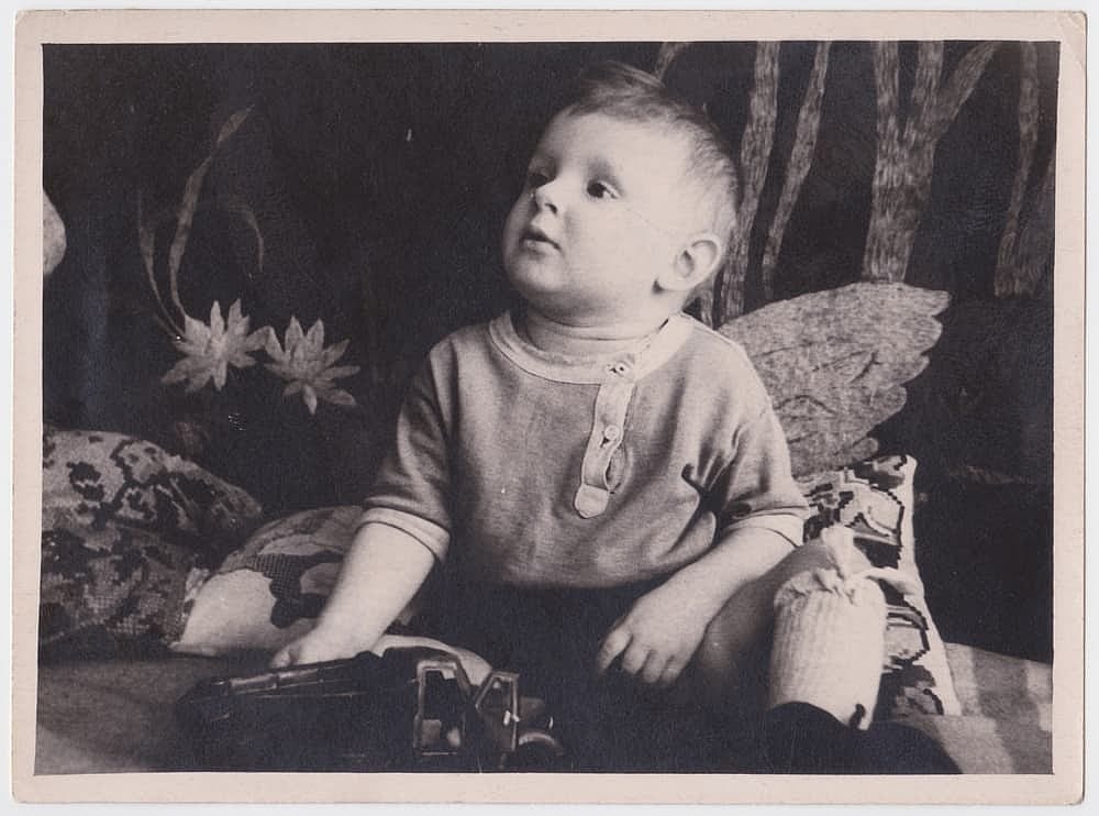Vintage black and white photo from the past. The photo shows a child with a Soviet toy.