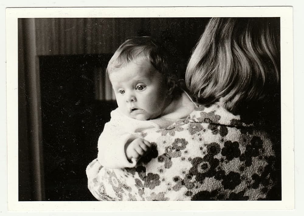 Vintage photo shows mother cradles baby in 1960s