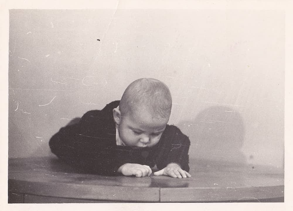 Old cute photo of a baby on a bed. Vintage black and white photo, slightly yellowed from time to time, taken in the USSR around the 1960s-1970s.