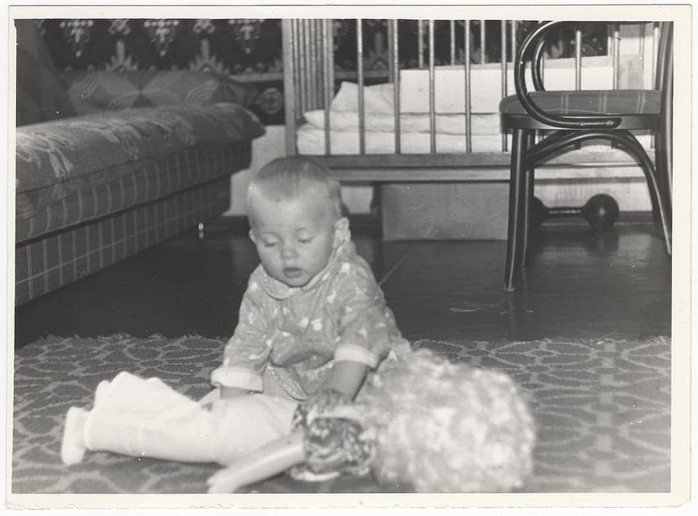 Vintage photo of a child playing on the floor with a doll. Old black and white retro photo, slightly yellowed by time, taken in the USSR around the 1960s