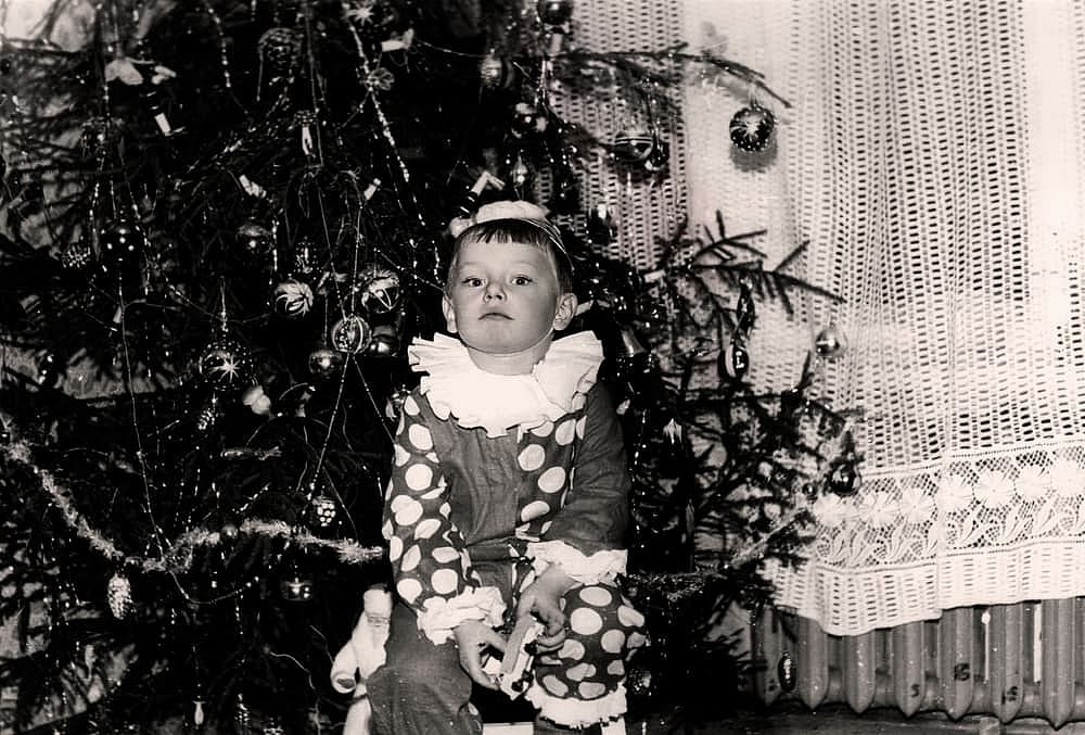 Vintage portrait of a little boy in a New Year's costume near a Christmas tree. Retro photo from 1960.