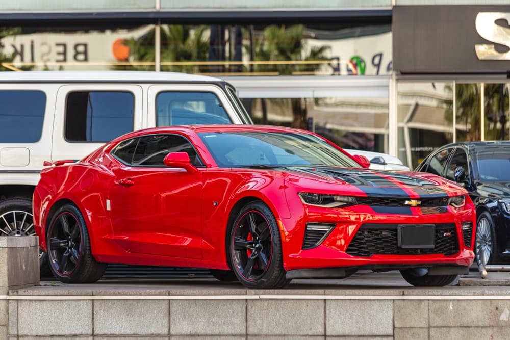 Red Chevrolet Camaro ZL1 supercharged muscle car with black stripe.