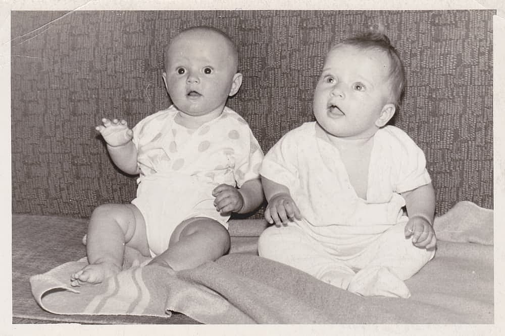 Vintage photo of two babies on a sofa. Old, slightly yellowed with time, black and white photo taken in the USSR around 1960-1970s.