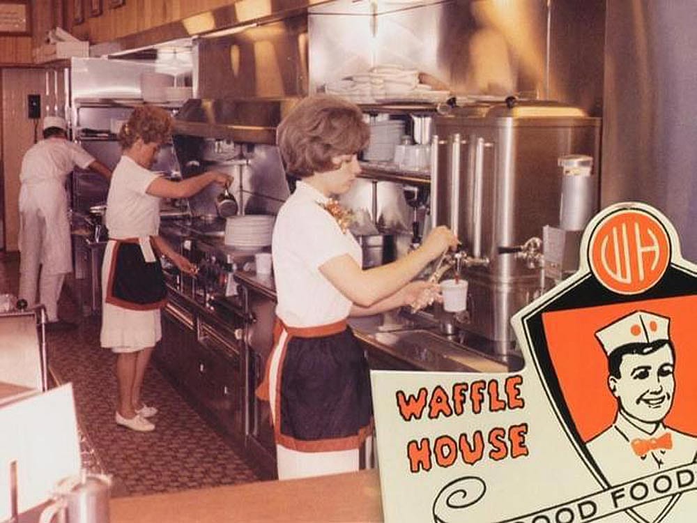 Two waitress and a cook behind the counter at a Waffle House.