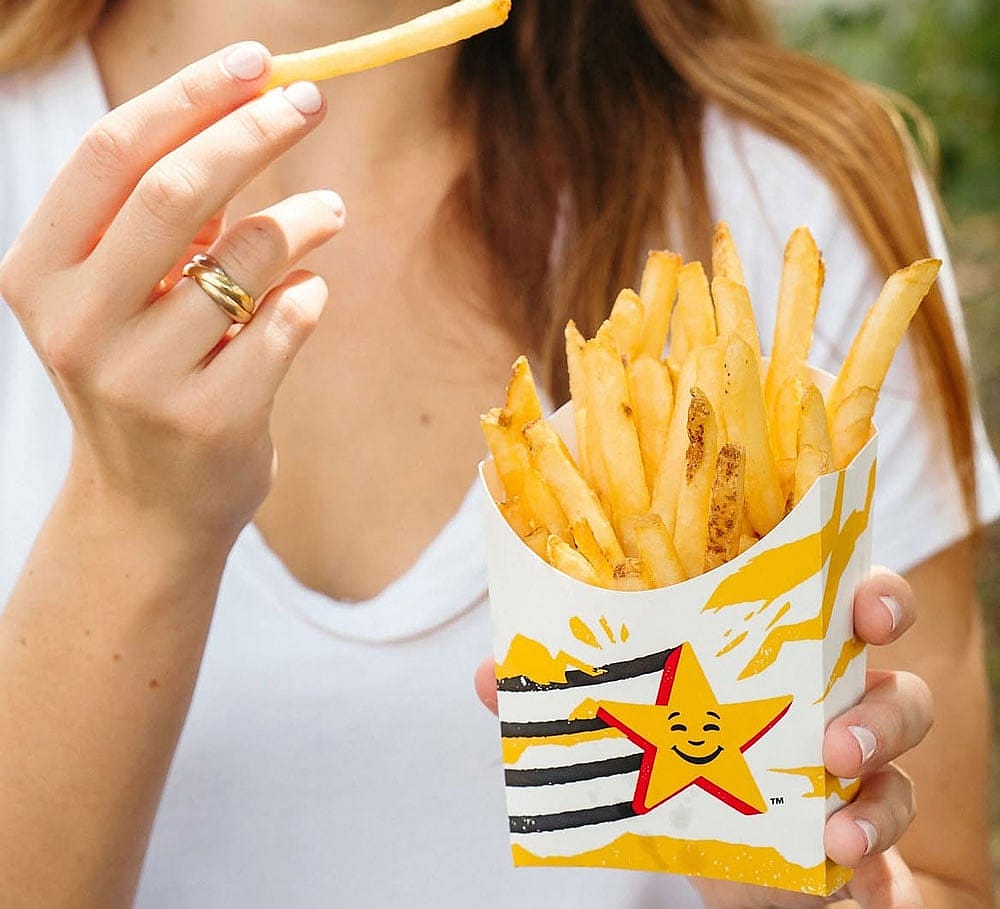 A woman holding a box of Hardee's french fries