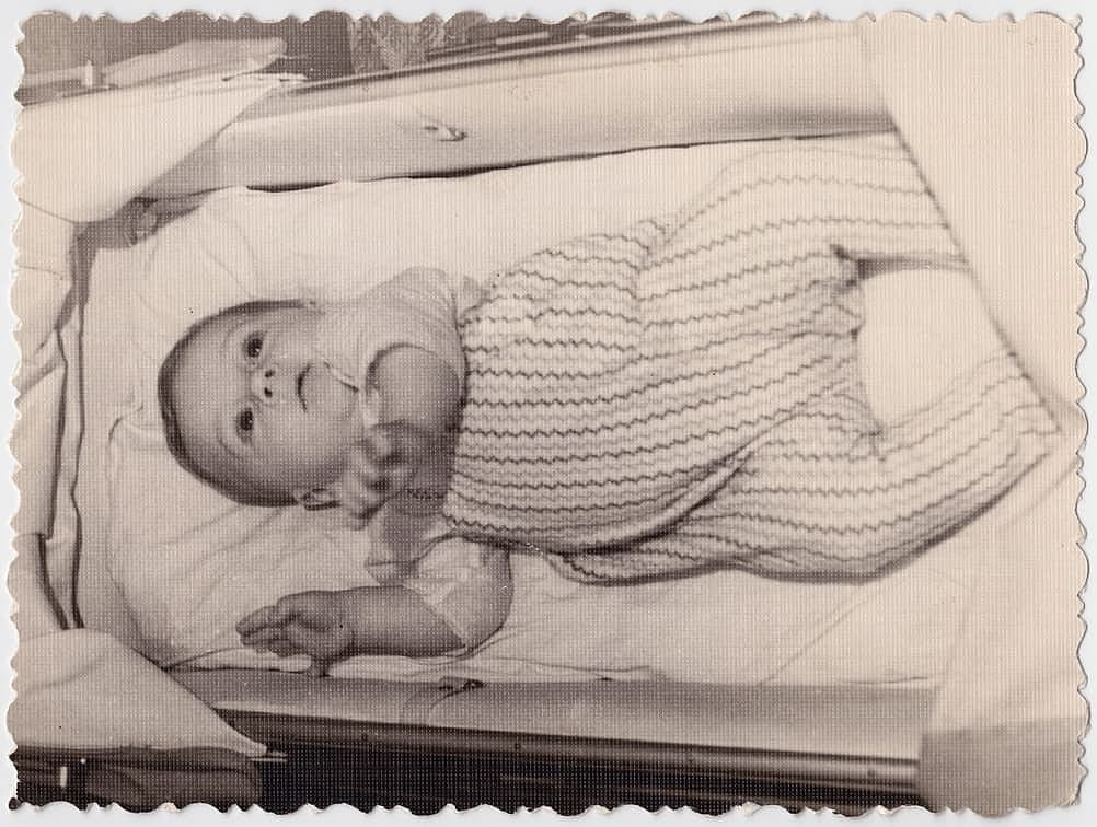 An interesting old photograph of a baby in a stroller. The photo has a pleasant vintage charm. This black-and-white retro shot was taken in the USSR in the 1960s.