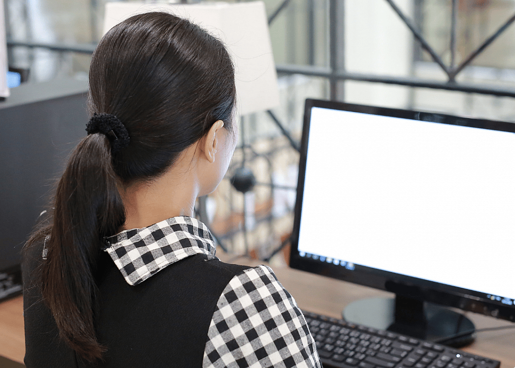 A woman at a desk works on a computer.