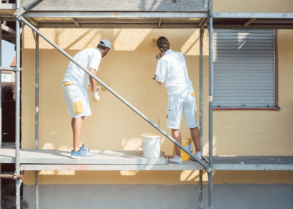 Painters work on scaffolding. 