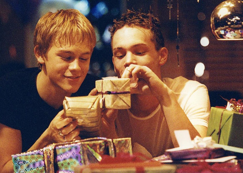 Two guys opening presents.