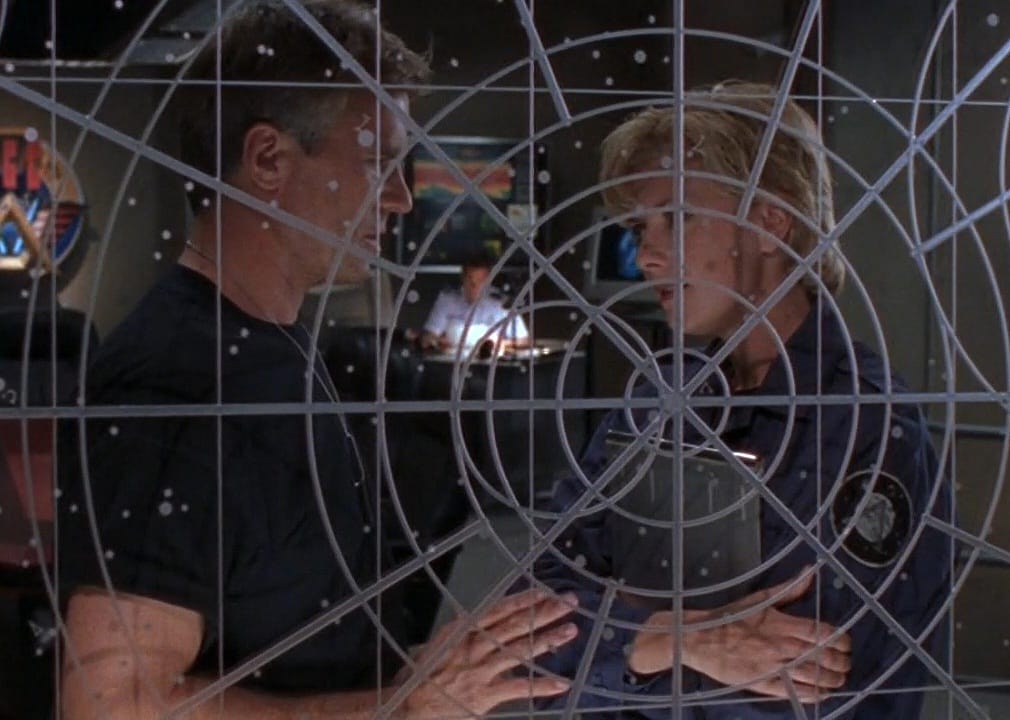 Two officers on a ship standing behind a clear planning board.