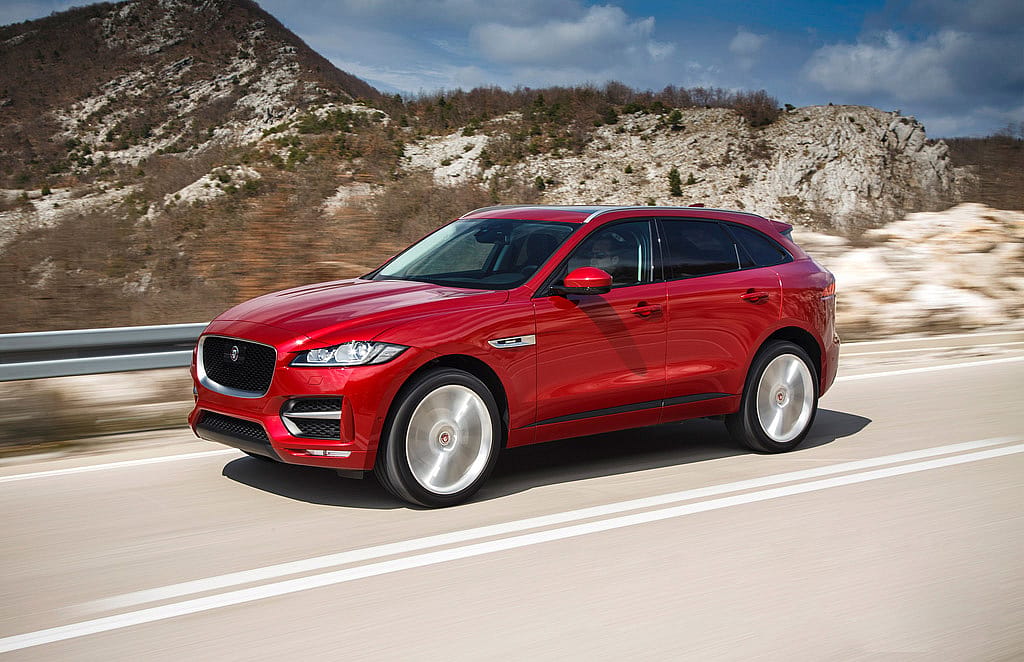 Red Jaguar F-Pace driving on the road.