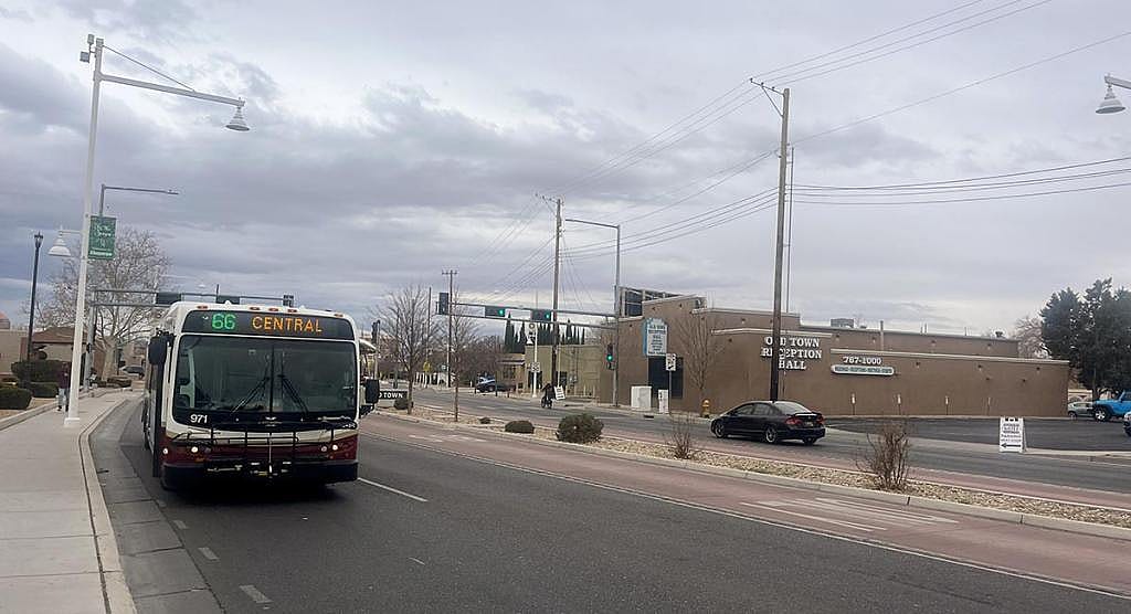 Bus driving on road toward viewer with destination "66 Central" showing, grey cloudy day in the background.