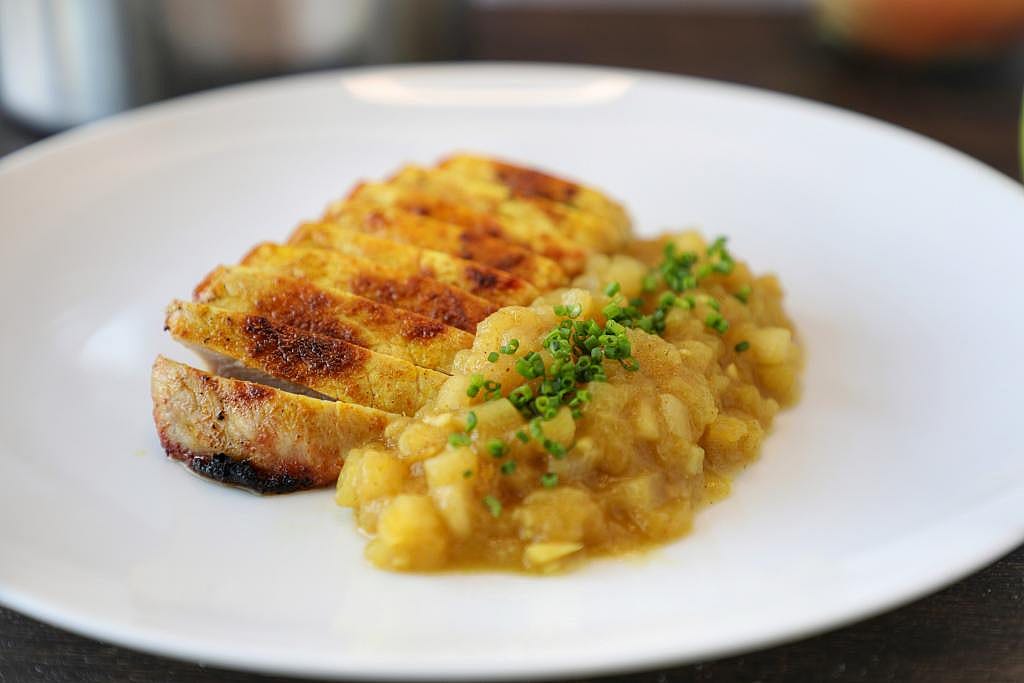 A plate of sliced grilled porkchop with apple chutney.