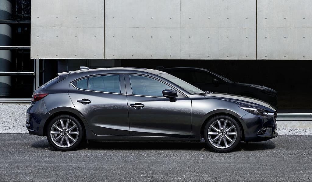 Black Mazda 3 parked in front of concrete building.