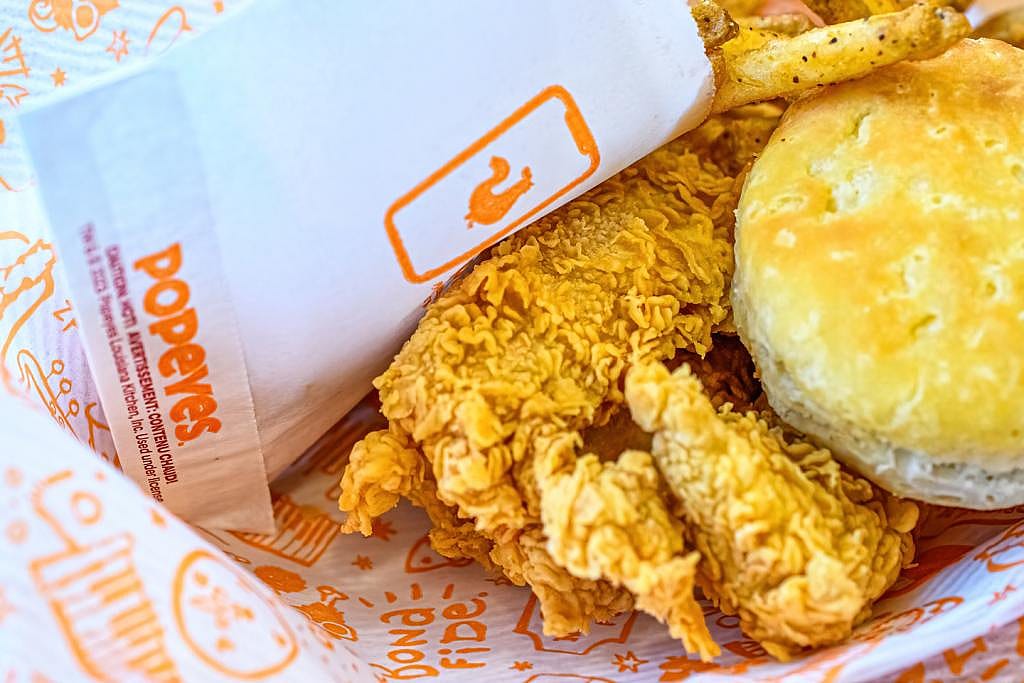 Cooked white meat, bread, and paper bag for french fries. Scene at a Popeye's fast food restaurant