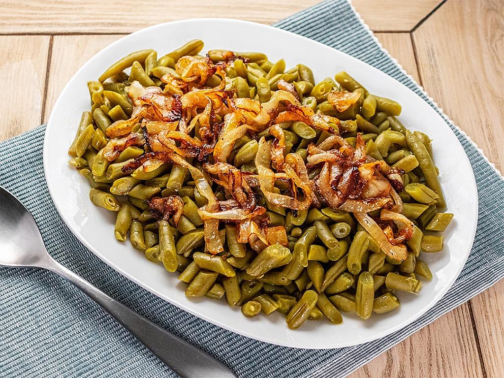 A plate of sautéed green beans with caramelized onions.