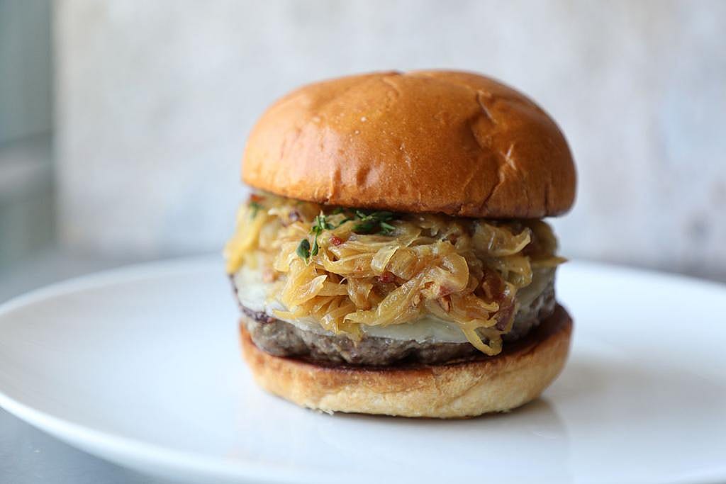 A plate of grilled bison burger with caramelized onions.