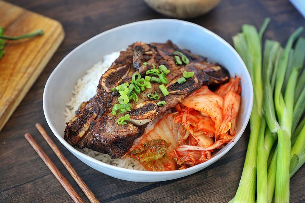 A plate of Galbi or grilled Korean beef short ribs with kimchi and rice.