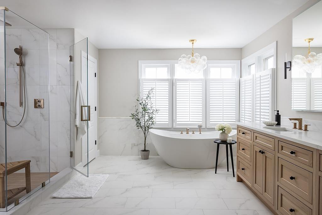 Bathroom with white marble floor and shower tiles and a standalone soaking tub.