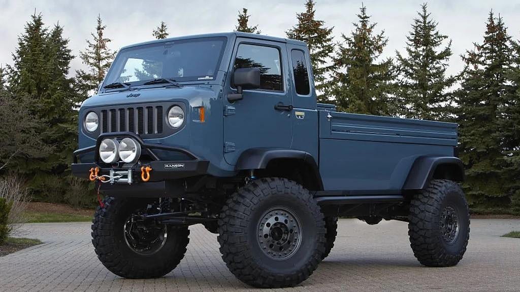 Blue Jeep Mighty FC Concept parked on pavement with trees in background.