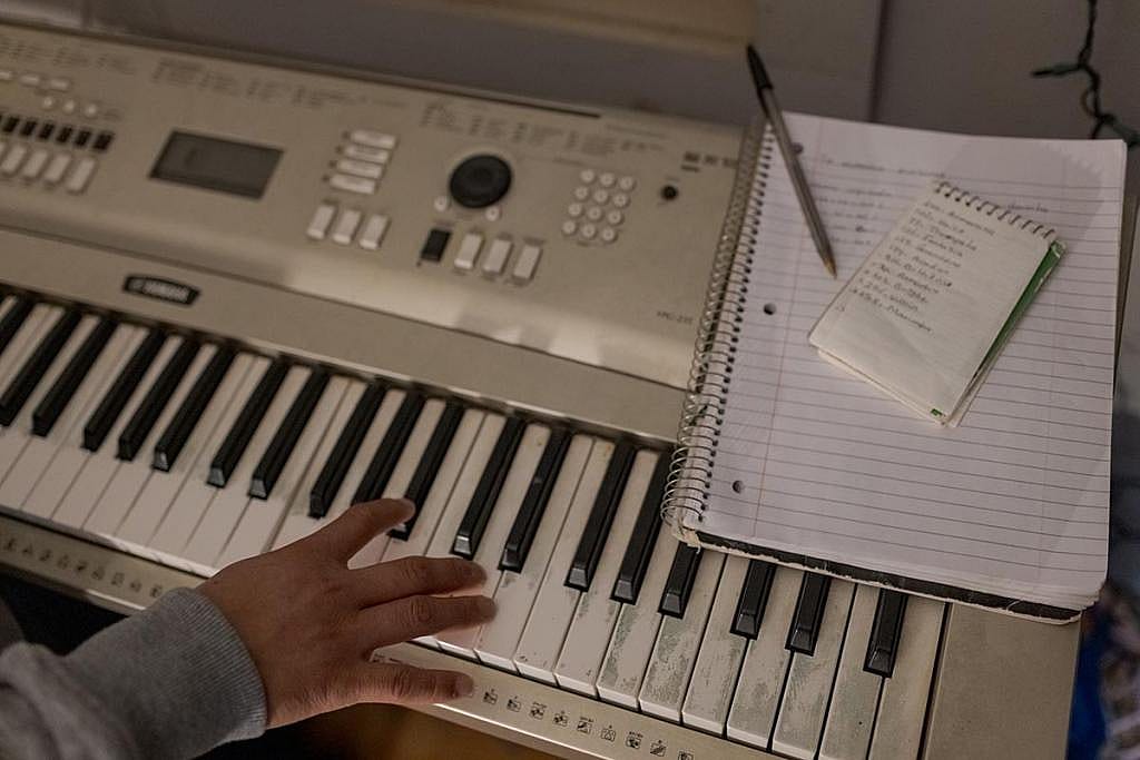View of one hand on a white keyboard next to where a notepad and notebook sit.