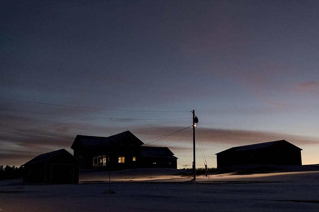 Scenes of rural Vermont in the winter, with buildings silhouetted against a sunset sky, snow on the ground, and no people visible outside.  It’s increasingly difficult for farm workers to cross the border to get back home.