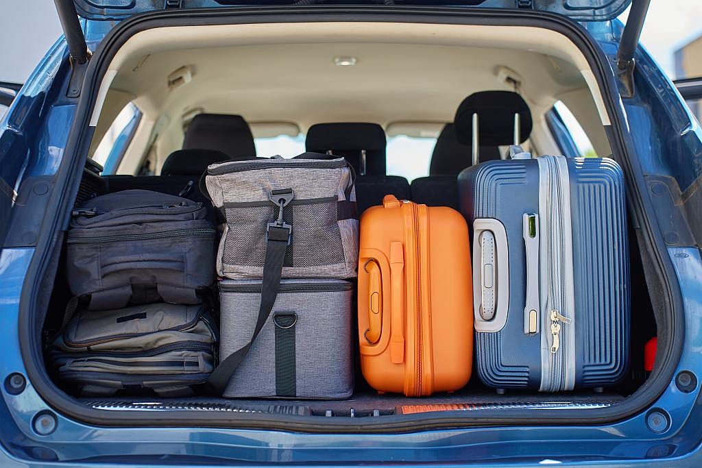 A car trunk packed with backpacks, bags, and suitcases before a road trip.
