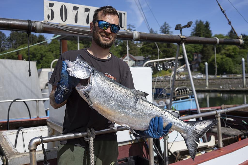 From fisherman Brett Montague holds a large fish with both hands. He supplies Local Ocean with 30,000 pounds of albacore a year.
