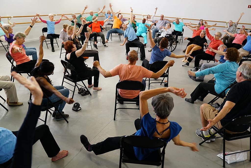 High-angle view of a room full of people dancing while in folding chairs.