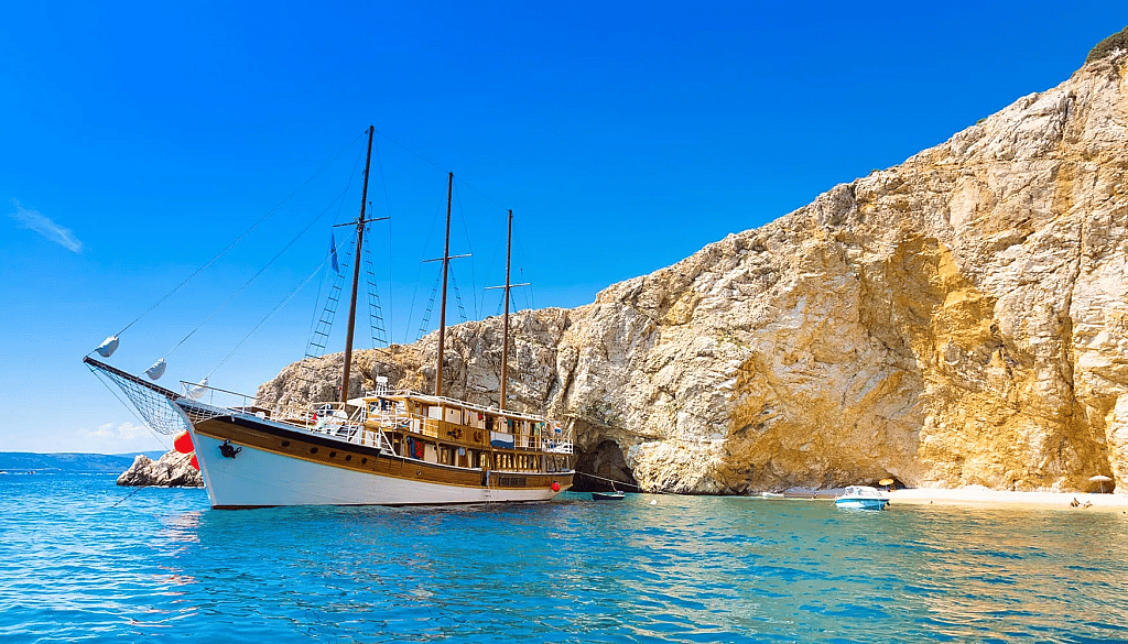 A wooden motor-sailing vessel anchored in a secluded cove in Croatia.