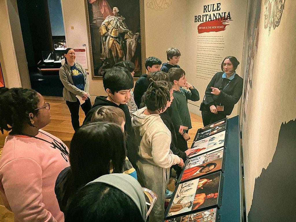 Samantha Dowis (rear left) looks on as tour guide Christina Gioia (right) takes her students through an exhibit at the Museum of the American Revolution.